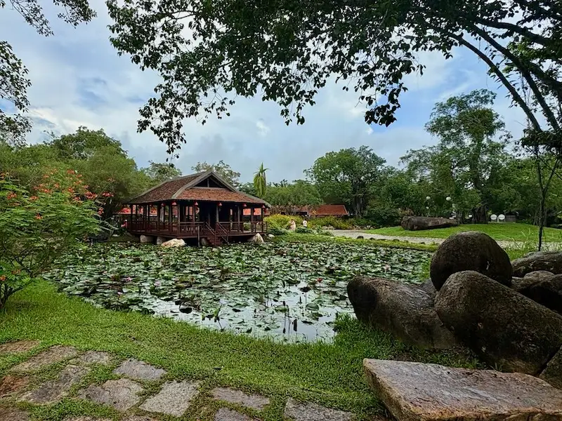 Традиционный деревянный павильон в стиле вьетнамской деревни, расположенный над прудом с лотосами в окружении пышной зелени грязелечебницы I-Resort в Нячанге.