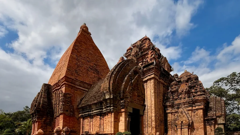 Древние кирпичные башни Понагар в Нячанге на фоне ярко-синего неба с облаками.