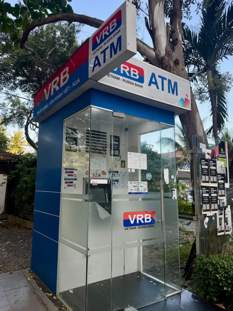 Уличный банкомат VRB (Вьетнамско-Российский банк) в Нячанге. Сине-белая стеклянная кабина с логотипом Vietnam - Russia Bank, где туристы могут снять наличные донги с карты МИР и карт unionpay.