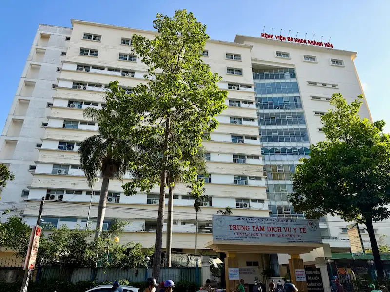 Фасад многоэтажного здания главной государственной больницы Bệnh viện Đa khoa tỉnh Khánh Hòa с красной вывеской на крыше в Нячанге, Вьетнам