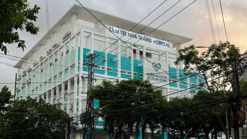 Крупным планом: фасад современного здания частной больницы Tâm Trí Nha Trang Hospital с крупной синей вывеской в Нячанге, Вьетнам