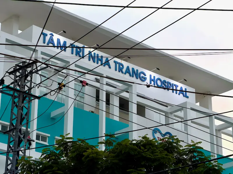 Фасад современного здания частной клиники Tâm Trí Nha Trang Hospital с крупной синей вывеской в Нячанге, Вьетнам